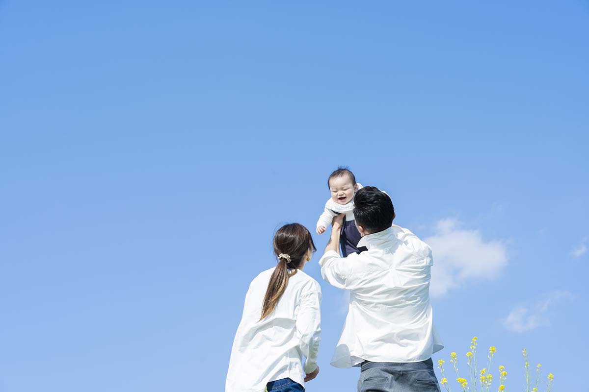 パパとパパと赤ちゃんが、青空の下で過ごしているイメージ